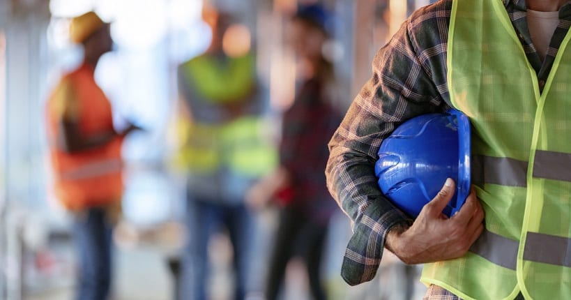 Man holding blue helmet during health and safety assesment