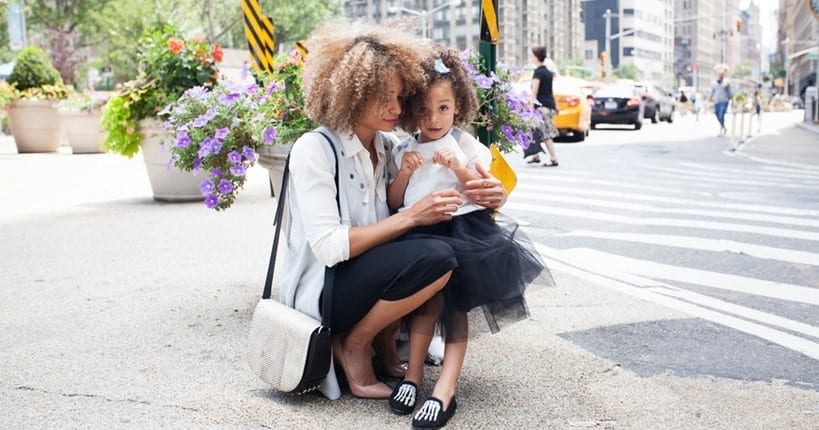 Formarly dresses woman holding daughter on street