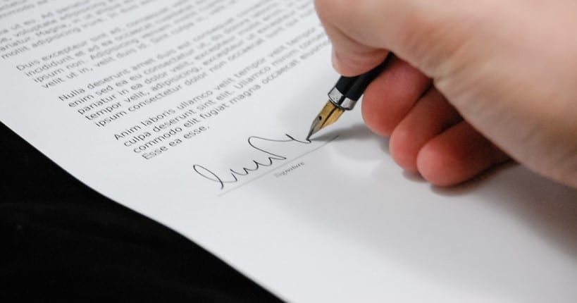 hand holding a pen signing a document