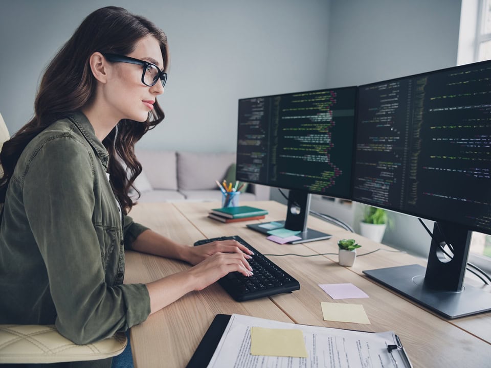 Woman in glasses writing a peace of code on computer